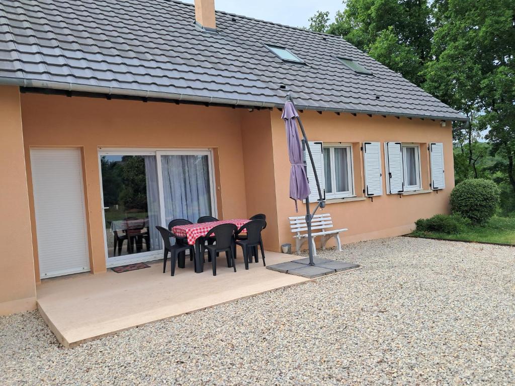 a patio with a table and chairs and an umbrella at Le Logis du Grand-Duc in Brignac-la-Plaine
