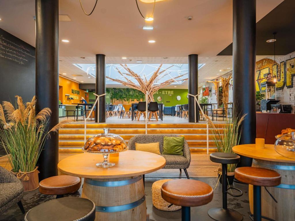 a restaurant with wooden tables and stools and a cafeteria at ibis Styles Calais Centre in Calais