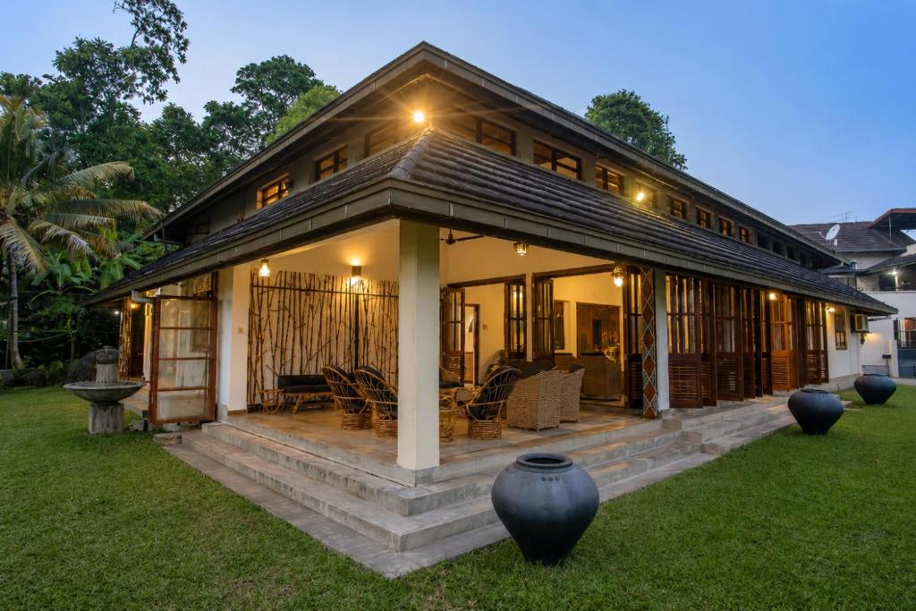 a house with a large porch with vases in the yard at Serenity Lake Front Villa in Moratuwa