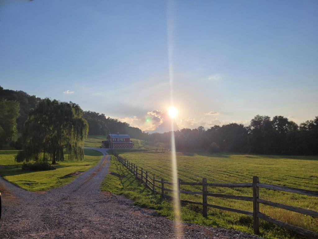 a sunset over a field with a fence and a road at FireFly Acres in Sparta