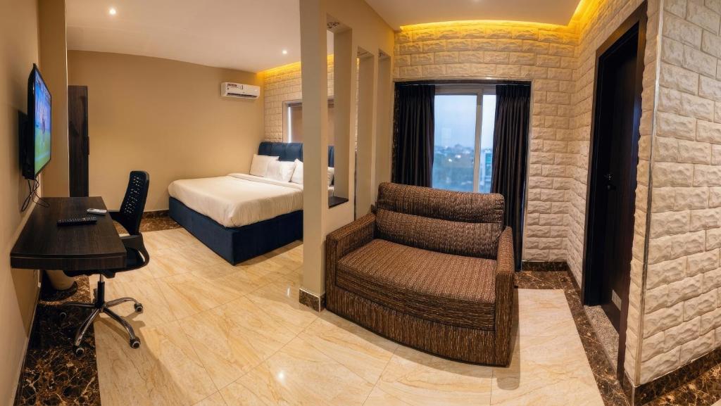 a bedroom with a bed and a chair in a room at Citistay Apartments in Abuja