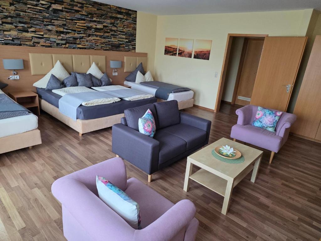a hotel room with two beds and a couch and chairs at Hotel Seerose Garni in Nohfelden