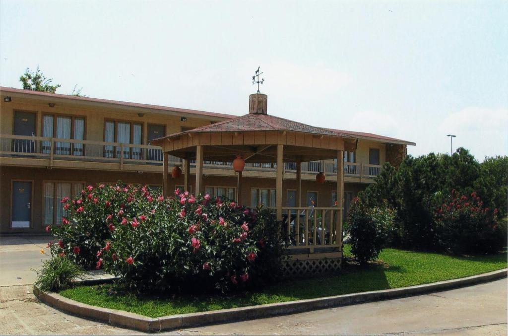 a gazebo in front of a building with flowers at Will Rogers Inn in Claremore