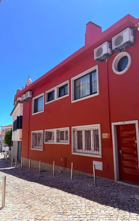 a red building with a red door and windows at Cascais Cosy Home - Rooms with Private Bathroom in Cascais
