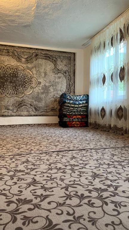 a room with a wall with a carpet and a window at House near the mountains in Karakol