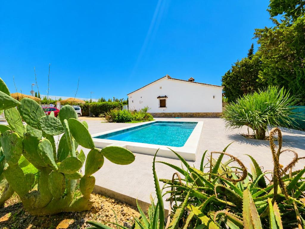 a villa with a swimming pool in a garden at Casa el Jilguero Conil in Conil de la Frontera
