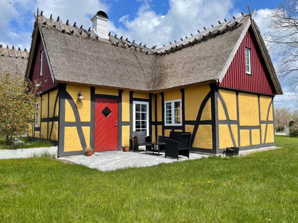 a yellow and red house with a red door at Charmig stuga i Abbekås in Abbekås