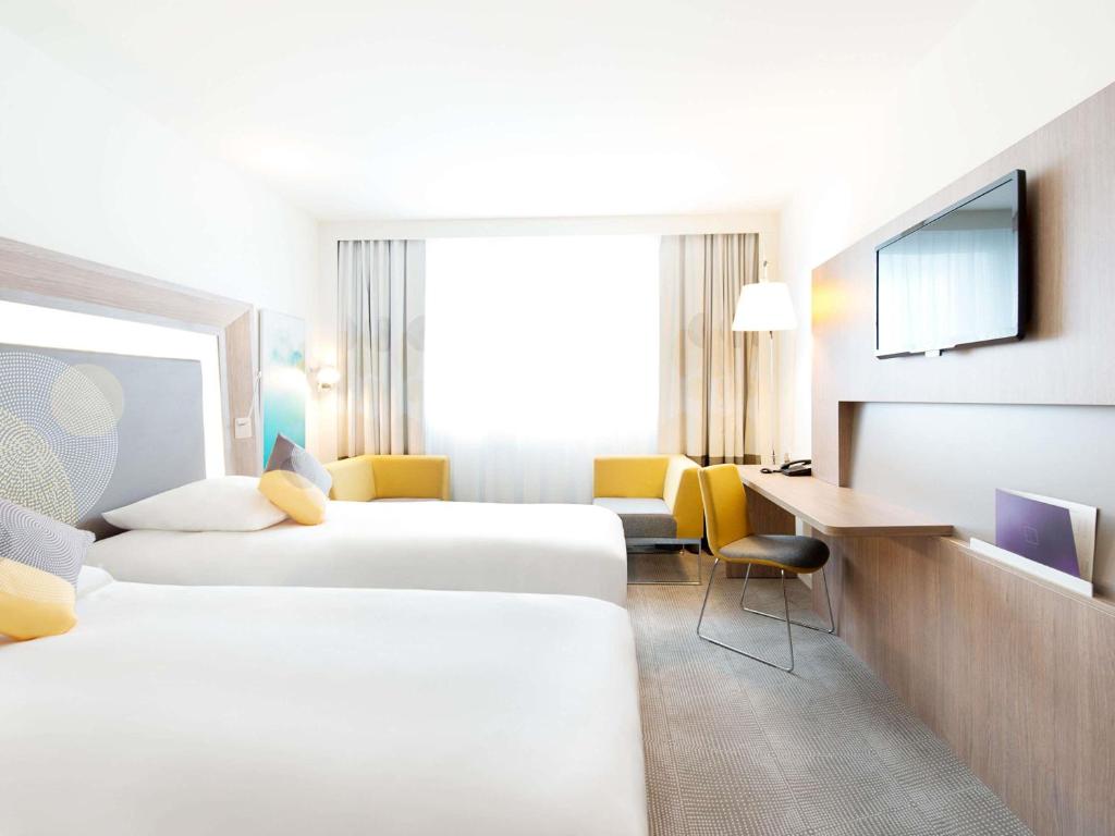 a hotel room with two beds and a desk at Novotel Lodz Centrum in Łódź