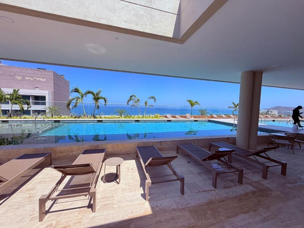 a swimming pool with tables and chairs in a building at Edificio Reserva del Mar Bello Horizonte in Playa Bello Horizonte