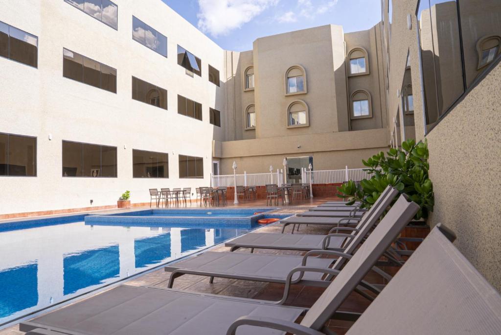 a swimming pool with lounge chairs next to a building at Al Diyar Hotel in Nizwa
