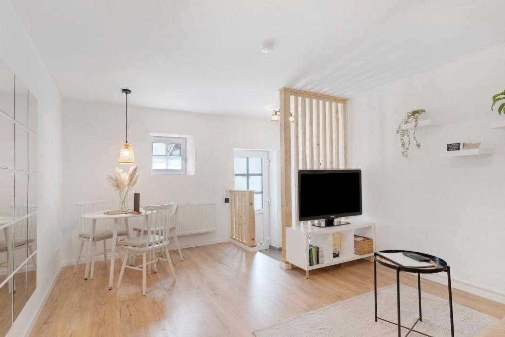 a white living room with a tv and a table at Ferienwohnung Tromei-Hof in Oberderdingen