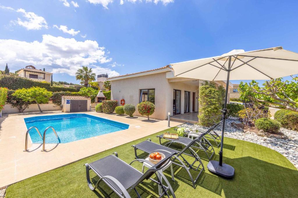 a pool with chairs and an umbrella next to a house at Villa Sea Side in Polis Chrysochous