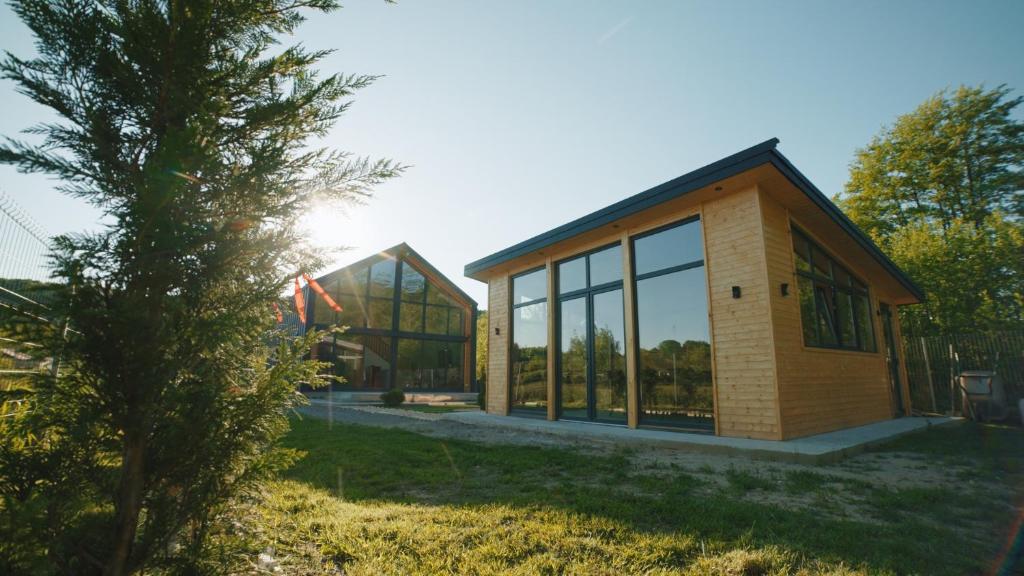 a house with glass windows and a tree at Nordic Cabin in Bughea de Jos