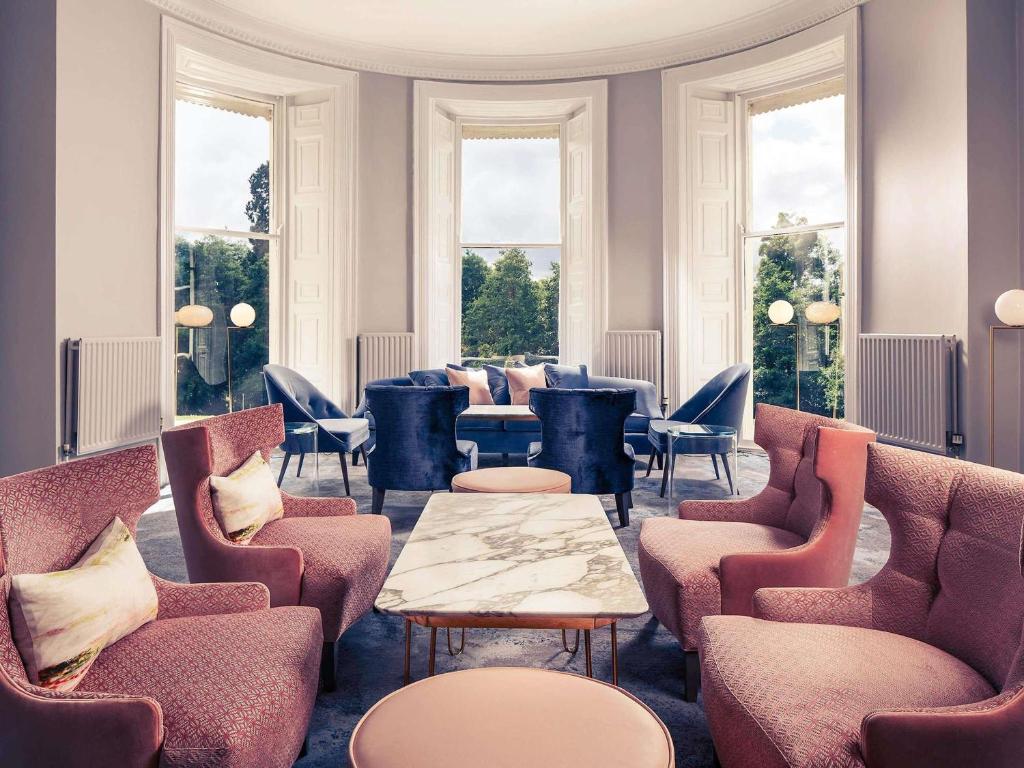 a waiting room with chairs and tables and windows at Mercure Gloucester Bowden Hall Hotel in Gloucester