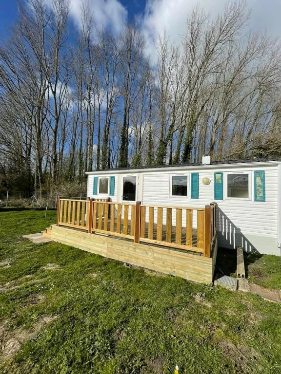 a mobile home with a wooden deck in a field at Ruben Bungalow in Bourbourg