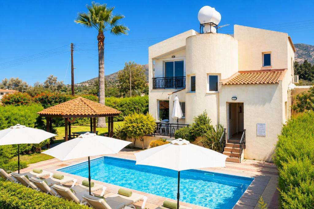 a villa with a swimming pool and umbrellas at Villa Sotiroula in Kato Yialia
