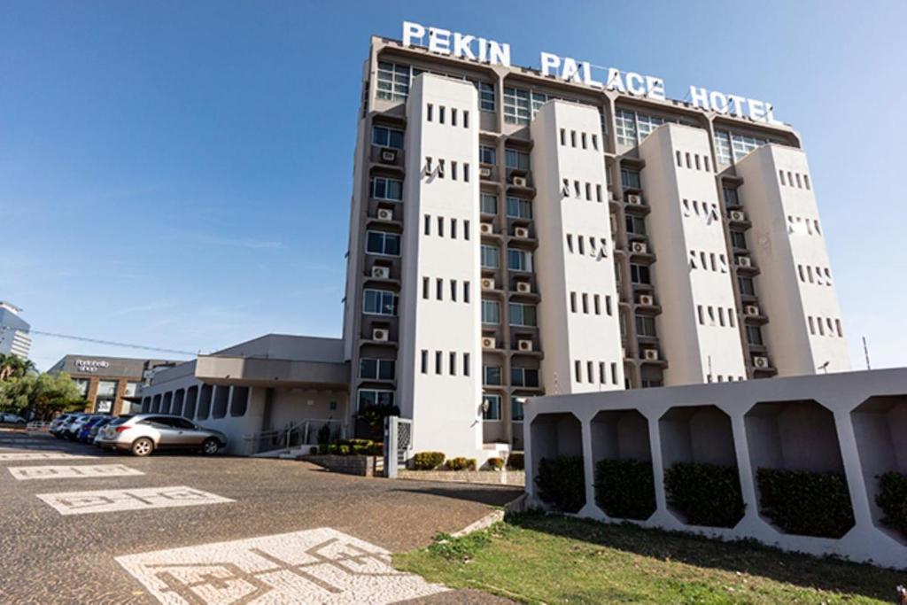 a building with a parking lot in front of it at Pekin Palace Hotel in Araçatuba