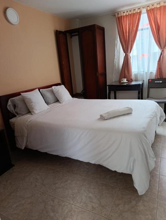 a bedroom with a large bed with white sheets at Hotel Surandino Fátima in Pasto