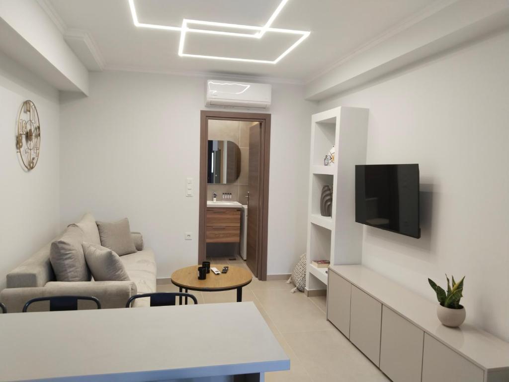 a white living room with a couch and a tv at Calm Horizon Residence in Chios