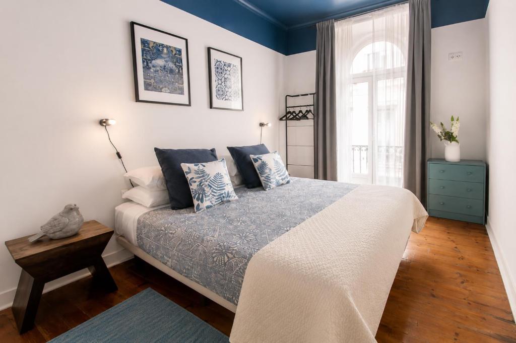 a bedroom with a bed with blue walls and a window at INT Lisbon Suites in Lisbon