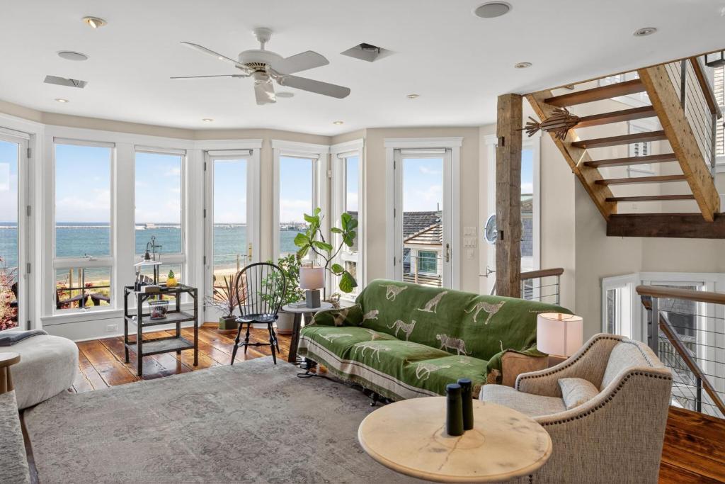 a living room with a green couch and windows at The Grand On Commercial in Provincetown
