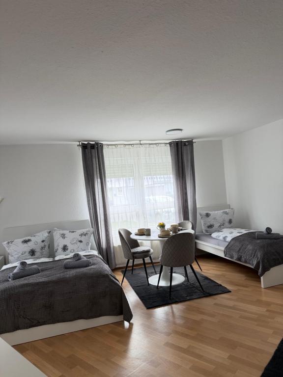 a bedroom with two beds and a table with a chair at Gemütliche Ferienwohnung in Sigmaringen in Sigmaringen
