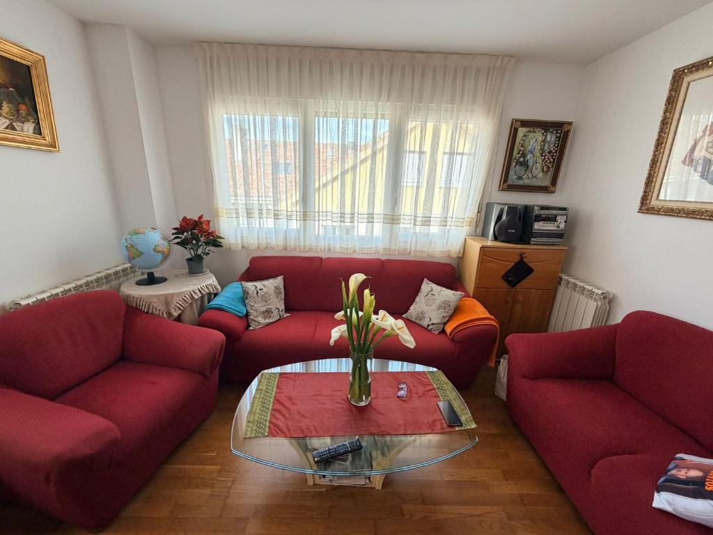 a living room with two red couches and a table at Apartamento Liencres in Liencres