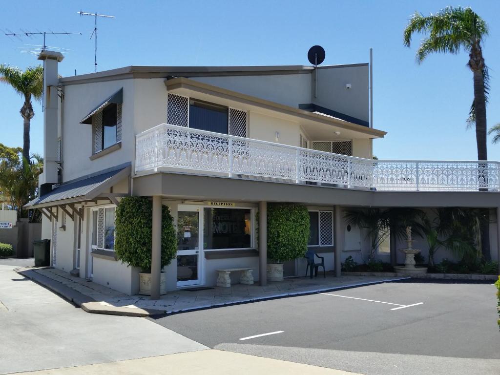 a white building with a balcony and palm trees at Mandurah Foreshore Motel in Mandurah