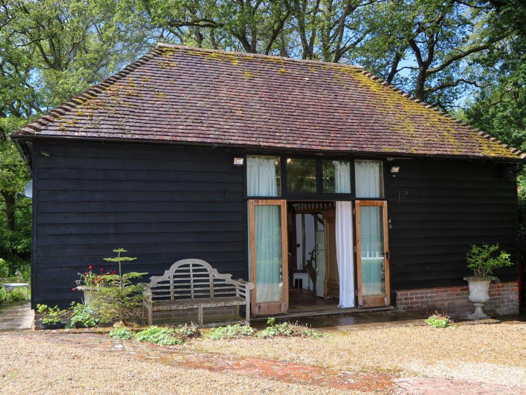 a small black house with a bench and a window at Petworth Barn in Petworth