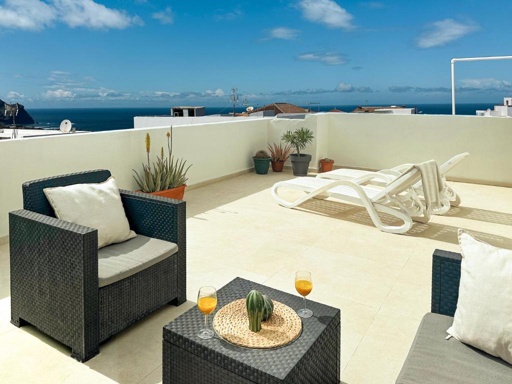 a patio with chairs and a table with wine glasses at Sunset Terrace Studio - Ocean View - Top Floor in Buenavista del Norte