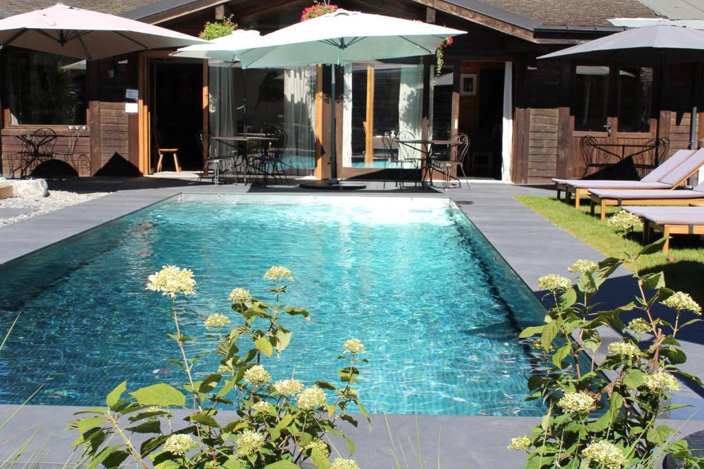 a swimming pool with an umbrella and some chairs and umbrellas at Fleur des Neiges in Morzine
