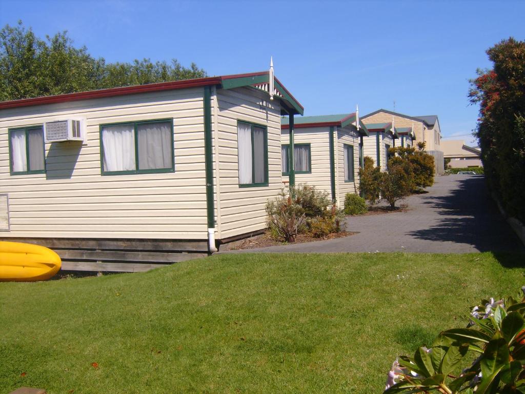 uma fila de casas móveis com um disco voador amarelo na relva em Inverloch Cabins & Apartments em Inverloch
