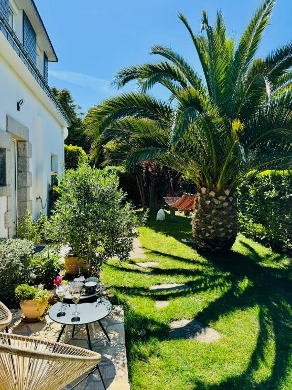a garden with a palm tree and a table and chairs at Entre Terre & Sel in Clohars-Carnoët