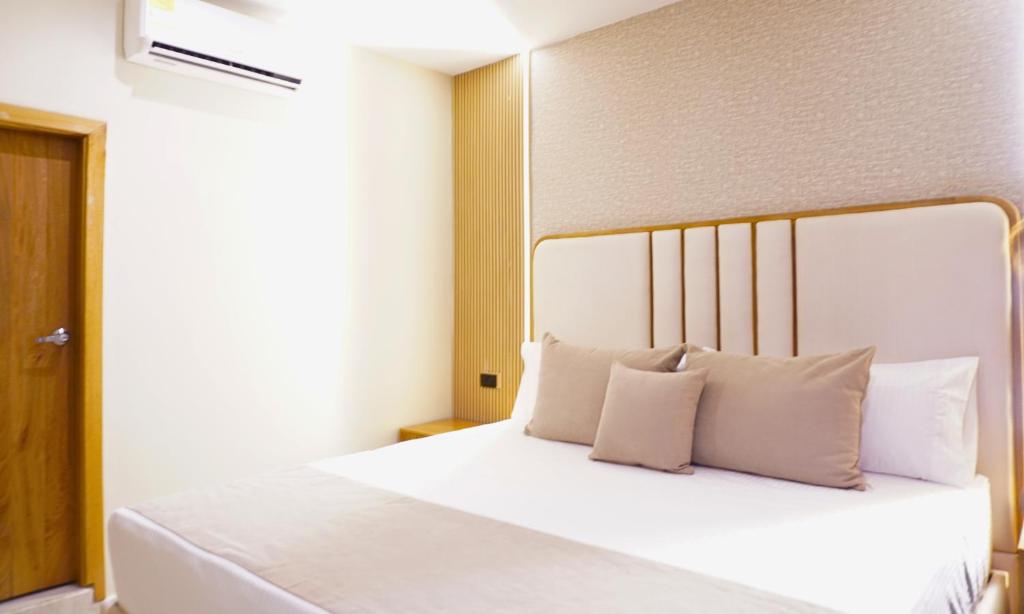 ein Schlafzimmer mit einem Bett mit weißen Laken und Kissen in der Unterkunft Zumo hotel lorica in Lorica