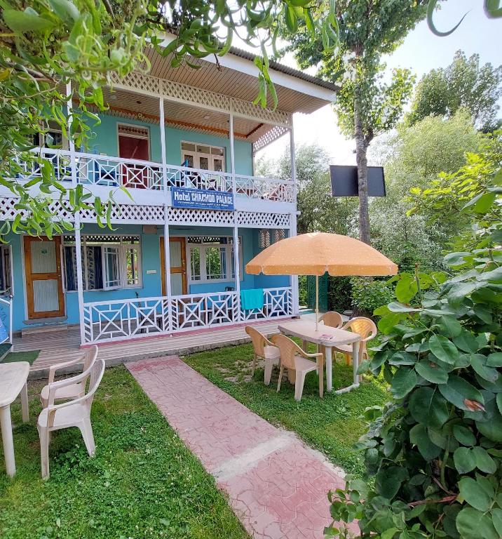 a house with a table and chairs and an umbrella at Hotel Chachoo Palace in Srinagar