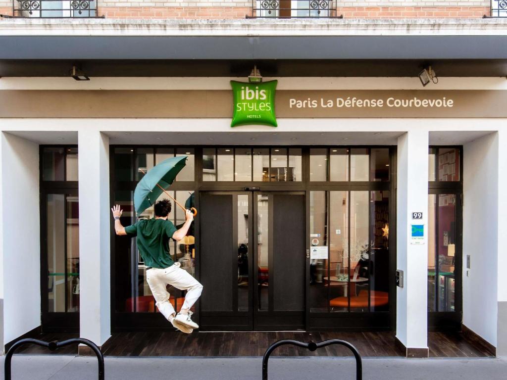 a man jumping in the air in front of a building at ibis Styles Paris La Défense Courbevoie in Courbevoie