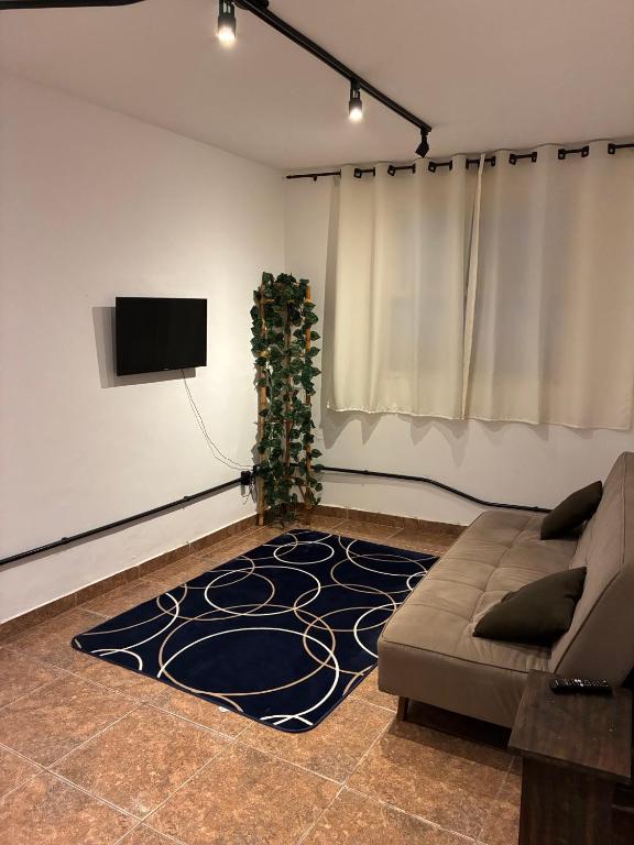 a living room with a couch and a flat screen tv at Apartamento em Petrópolis 1 quarto completo in Petrópolis