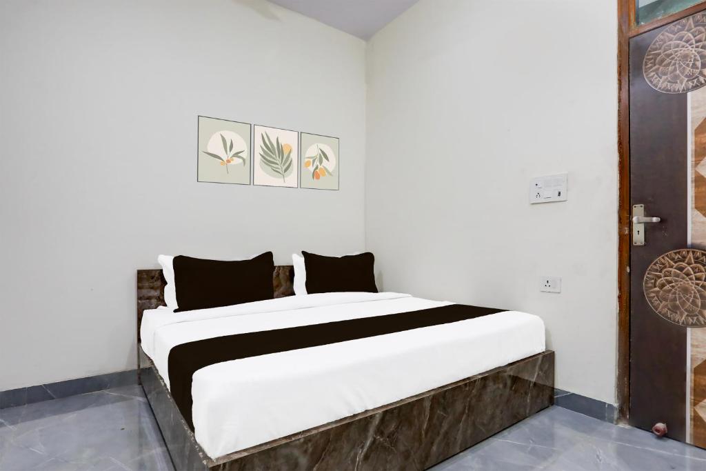 a bedroom with a large white bed with black pillows at Hotel O Kalka in Faridabad