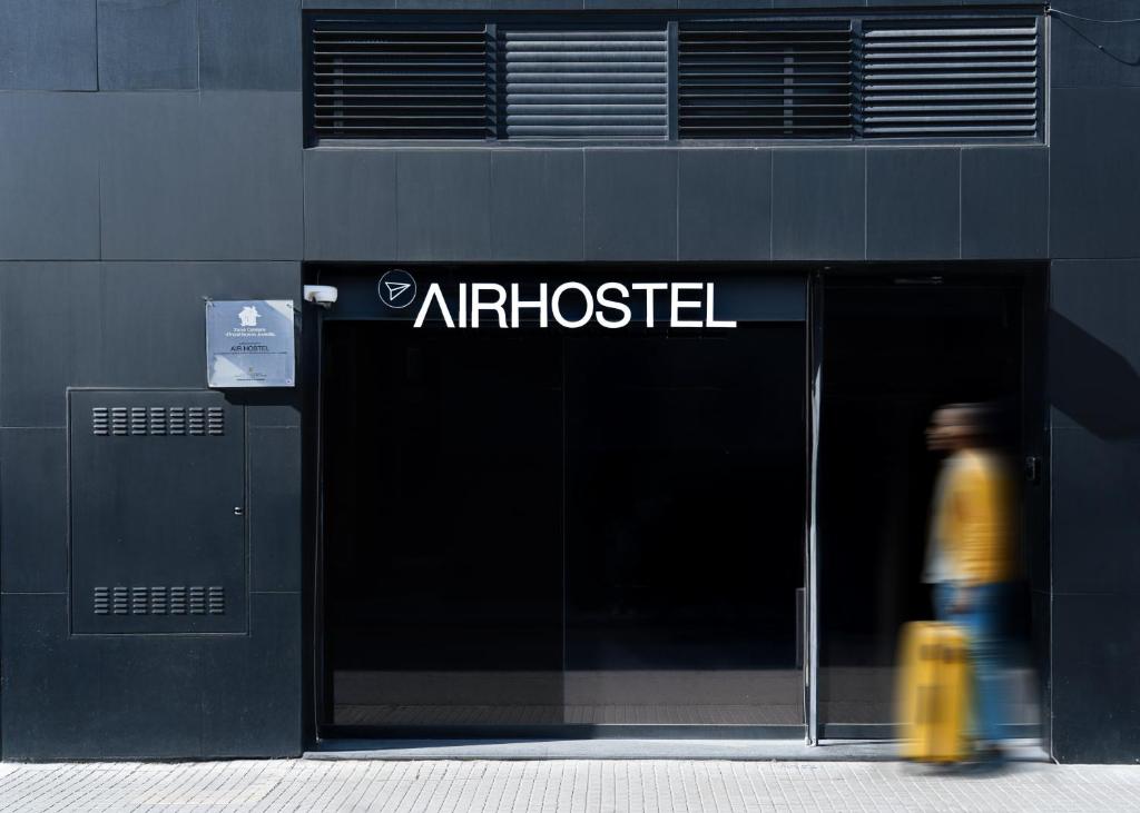 a person walking in front of an entrance to anadobeadobeadobe at Airhostel Barcelona Airport 24h in El Prat de Llobregat