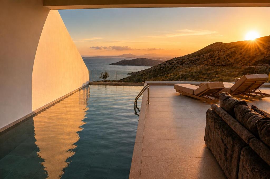 a pool with a view of the ocean at sunset at Anemolia Villas in Karpathos