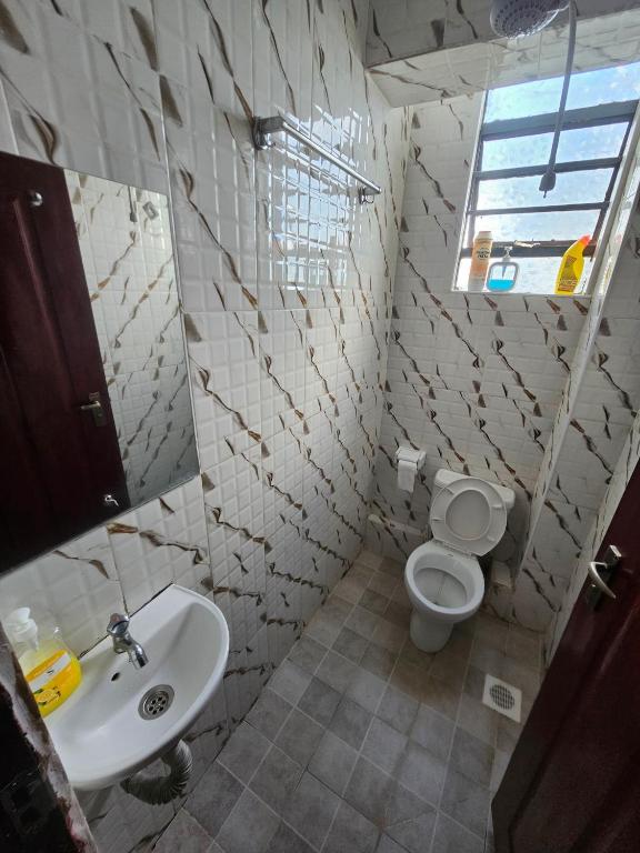 a bathroom with a sink and a toilet and a window at Pinnacle Homes 254 - Kamakis in Ruiru