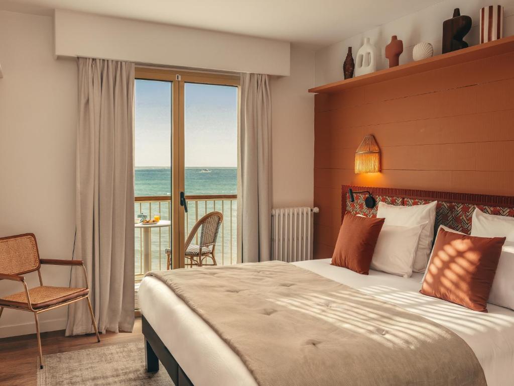 a bedroom with a bed and a view of the ocean at Hôtel Les Brises in La Rochelle