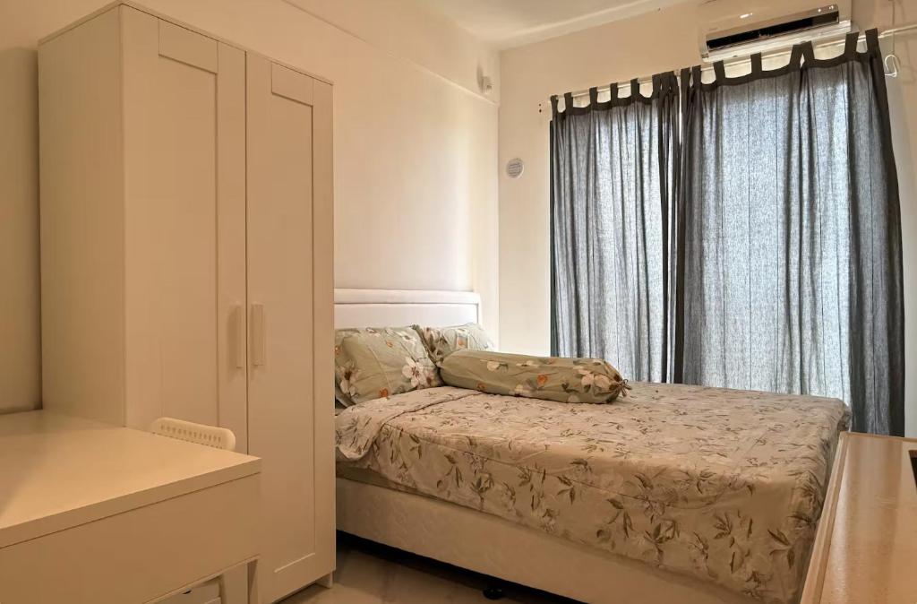 a small bedroom with a bed and a window at Calm & Comfy at Sky House BSD in Cilenggang
