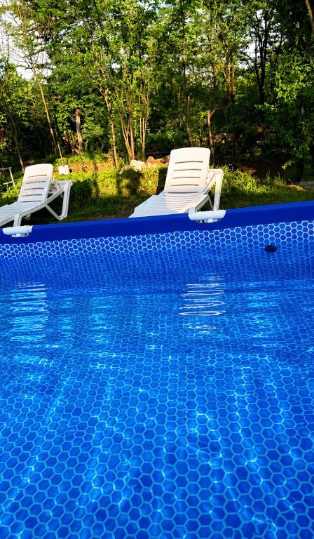 two white chairs sitting next to a swimming pool at Panorama Gora in Kutaisi