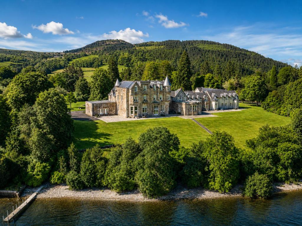 an aerial view of a large mansion on a grassy field at Lomond Castle Penthouse in Luss