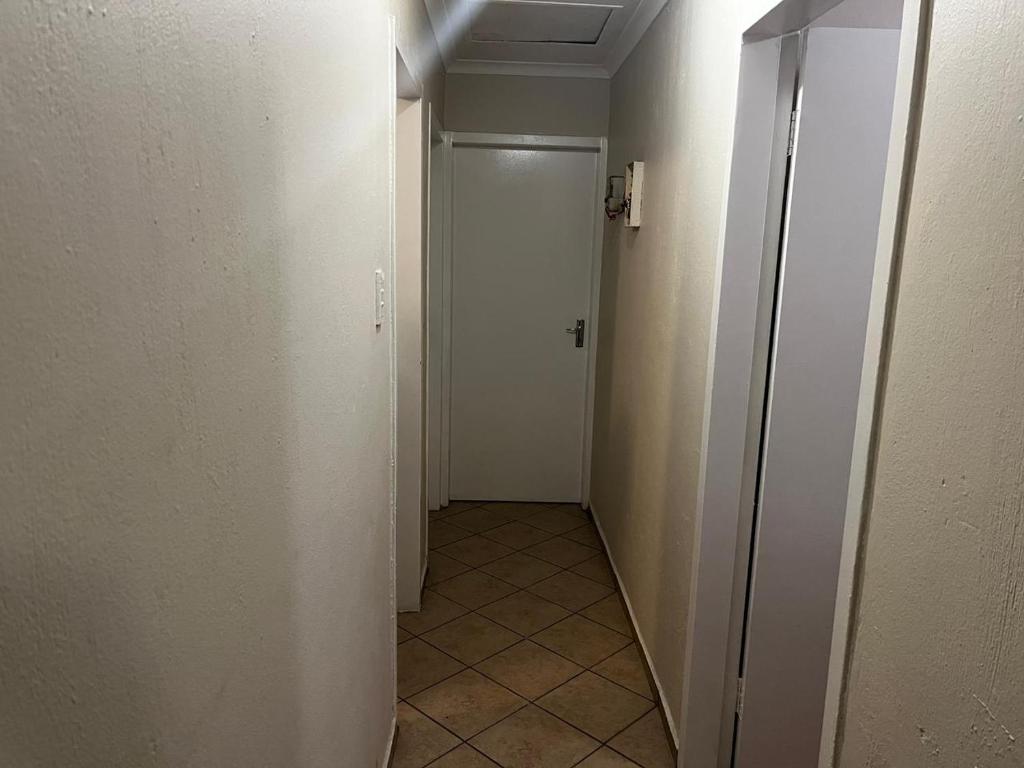 a hallway with a white door and a tile floor at Namahadi Stay in Vereeniging