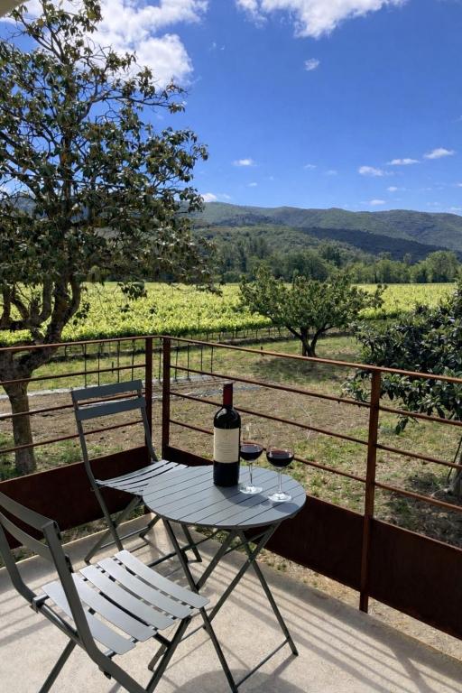 a table with a bottle of wine and a chair on a porch at Balcon sur les vignes - Loft de charme 2 pers in Cournanel