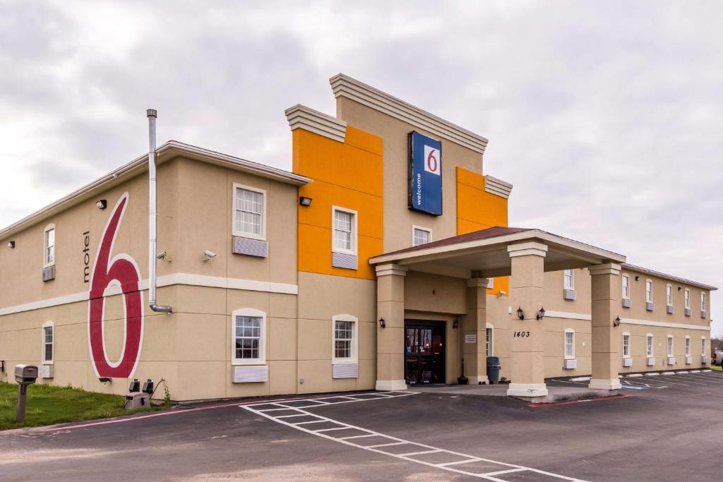a large building with a sign in a parking lot at Motel 6-Jourdanton, TX in Jourdanton