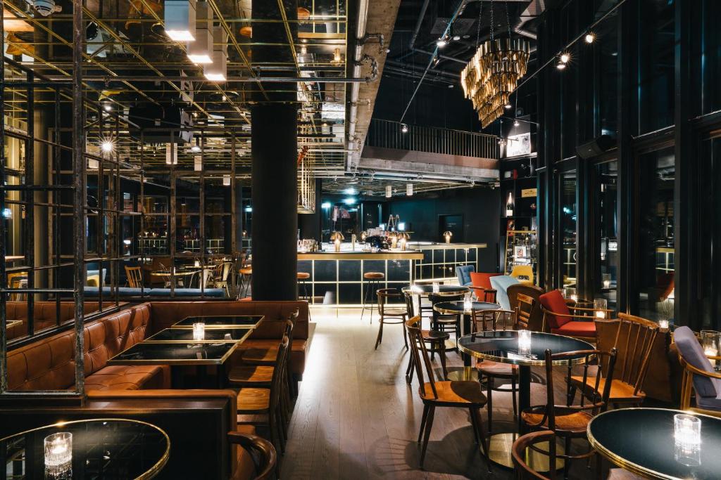 un ristorante con tavoli, sedie e un bar di Ruby Lilly Hotel Munich by IHG a Monaco