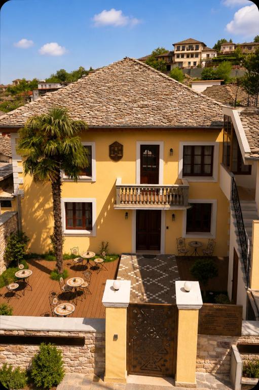 a yellow house with a balcony and a patio at Nostalgia Boutique Hotel in Gjirokastër